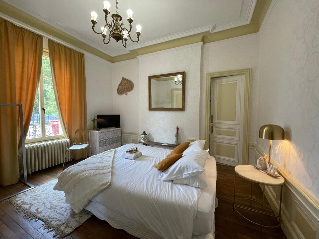 ein Schlafzimmer mit einem großen weißen Bett und einem Kronleuchter in der Unterkunft Gite L'Instant Champenois in Bréviandes