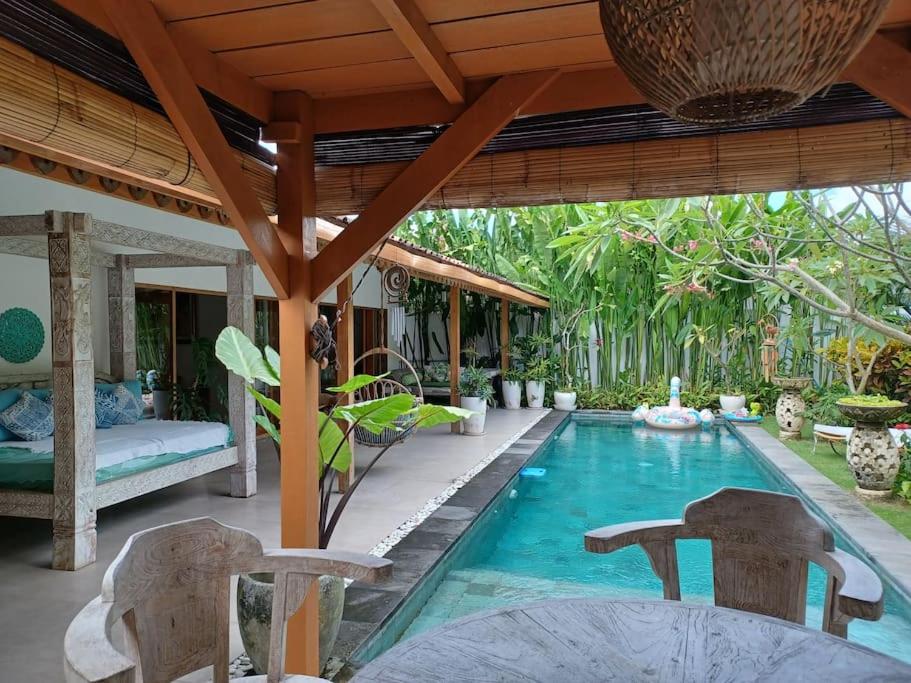 een zwembad in een villa met een tafel en stoelen bij Villa Emmylien in Dalung