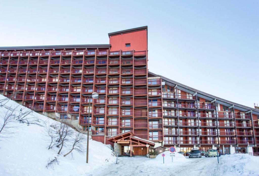 un grande edificio rosso con neve per terra di Résidence Le Varet - Arcs 2000 ad Arc 2000