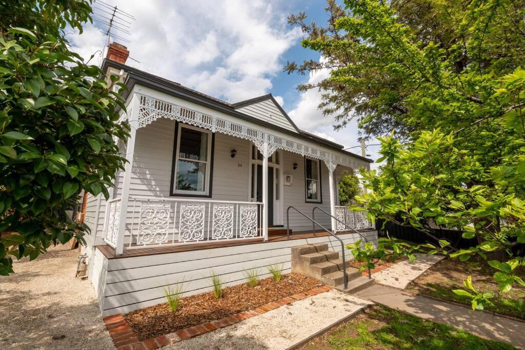 a white house with a porch and a balcony at Newly renovated, Kennedy Cottage - close to CBD in Bendigo