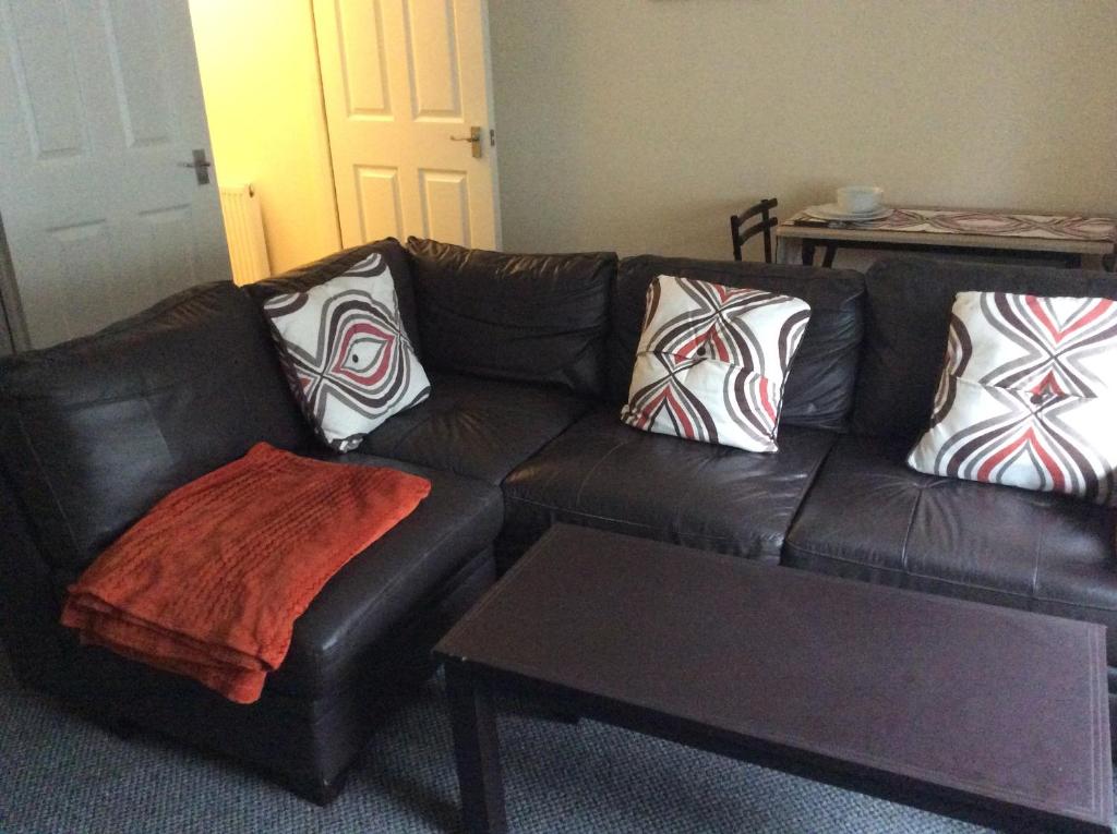 a brown leather couch with pillows and a coffee table at 103 Nelson Street Ground Right Largs in Largs