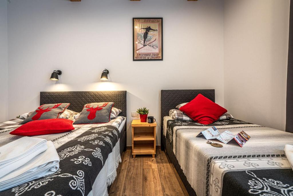 two beds in a small room with red pillows at Willa Mountain Centrum in Zakopane