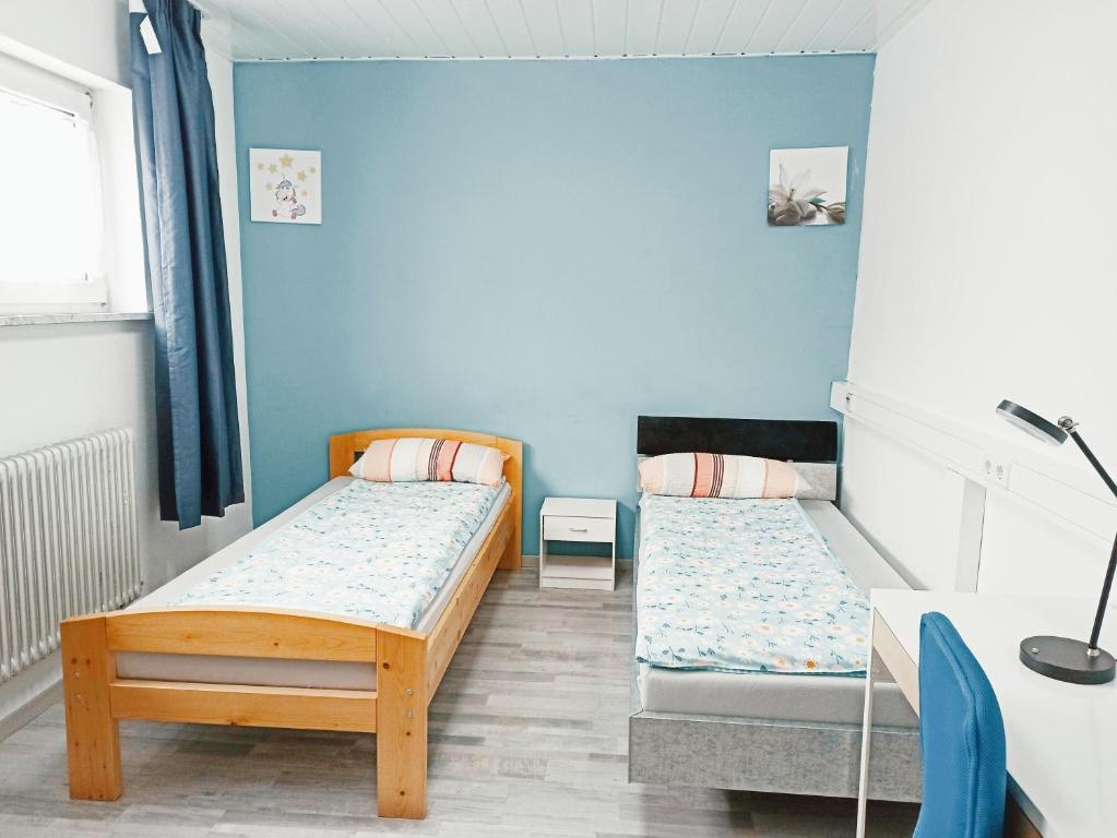 2 camas en una habitación con paredes azules en Charlotte House Heidelberg, en Dossenheim