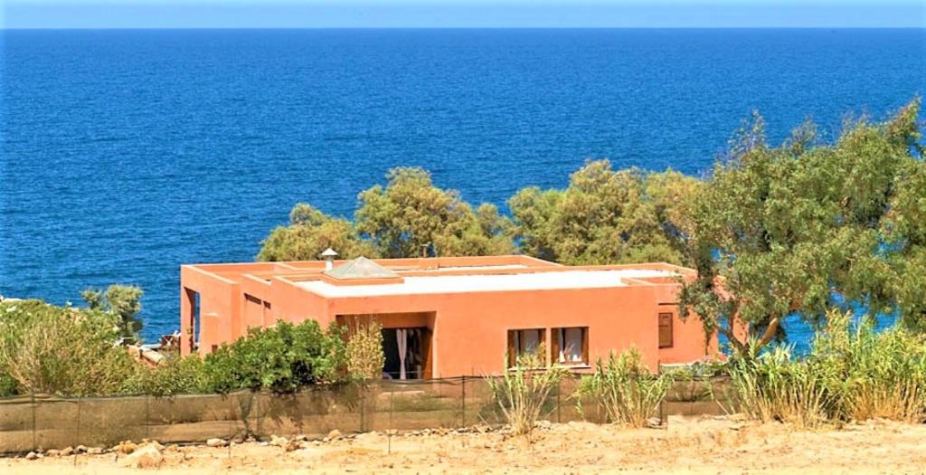 een oranje huis op een heuvel bij de oceaan bij Villa Rodialos in Panormos Rethymno