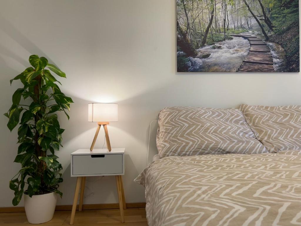 a bedroom with a bed and a plant and a lamp at 55 m2 Stylish Apartment with Balcony and Netflix in Vienna