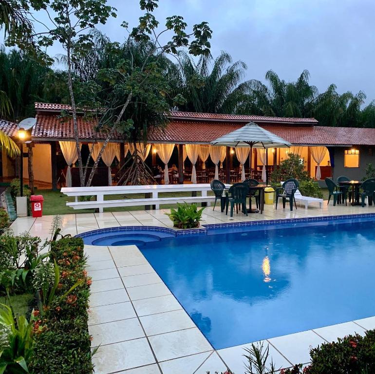 a resort with a swimming pool and tables and chairs at Amazônia ParkSuítes in Novo Airão