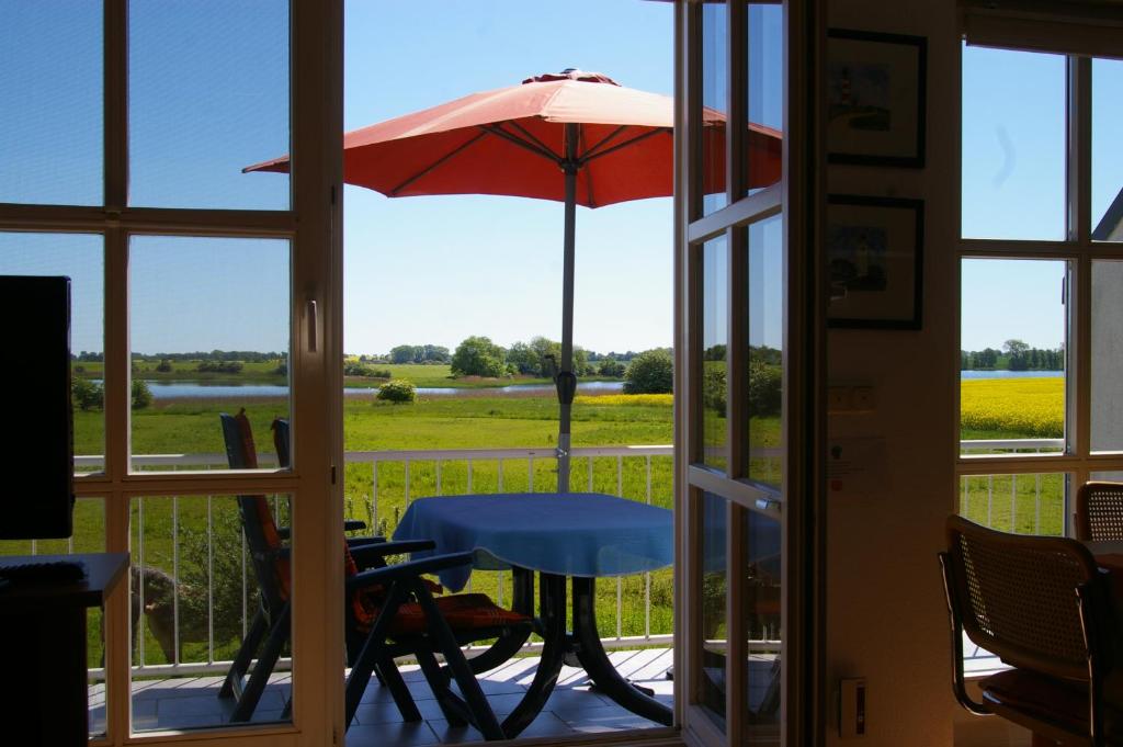 una mesa y una sombrilla en un porche en Ferienwohnung Boddenblick en Zudar