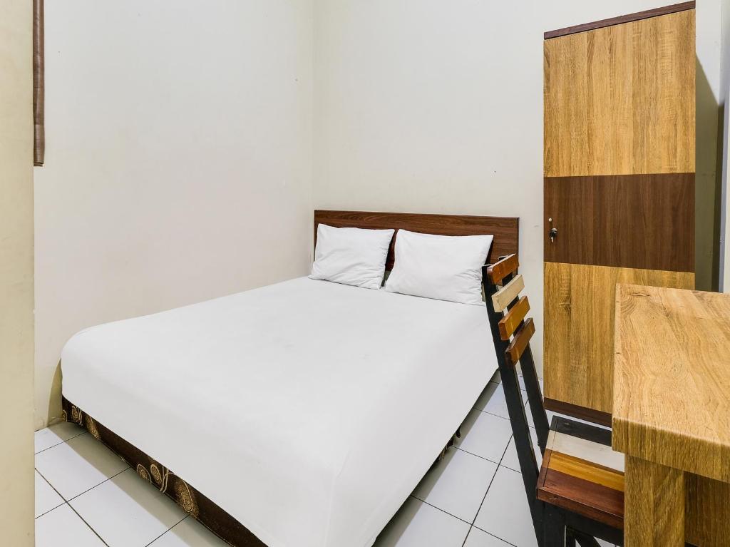 a bedroom with a white bed and a wooden cabinet at SPOT ON 2451 Camel Residence in Semarang