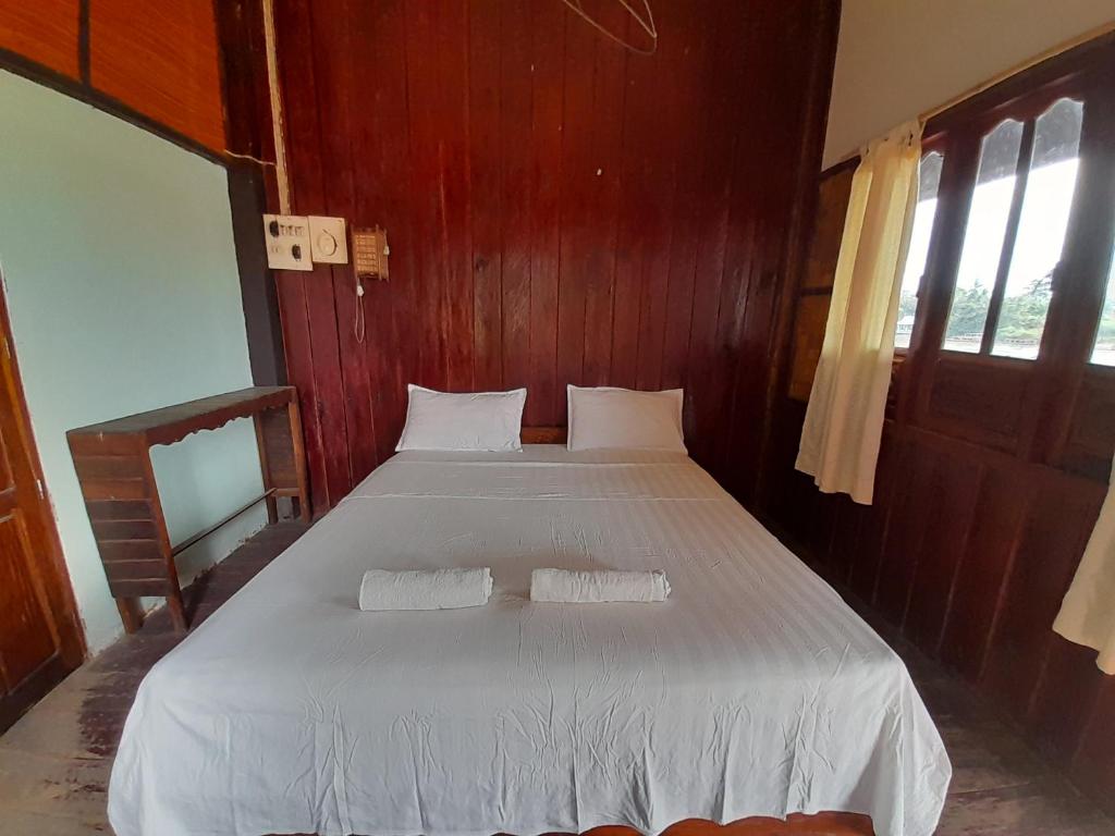 a bedroom with a large white bed with two pillows at Rivergarden Guesthouse and restaurant in Don Det