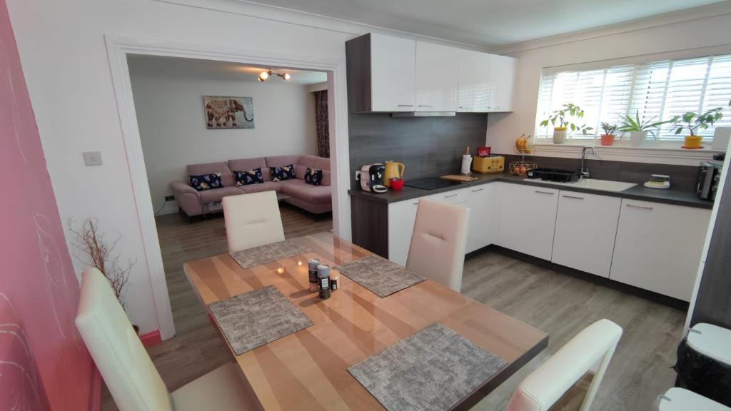 a kitchen and dining room with a wooden table in a room at Lovely 2 Bedroom Modern Ground Floor Flat in Clydebank