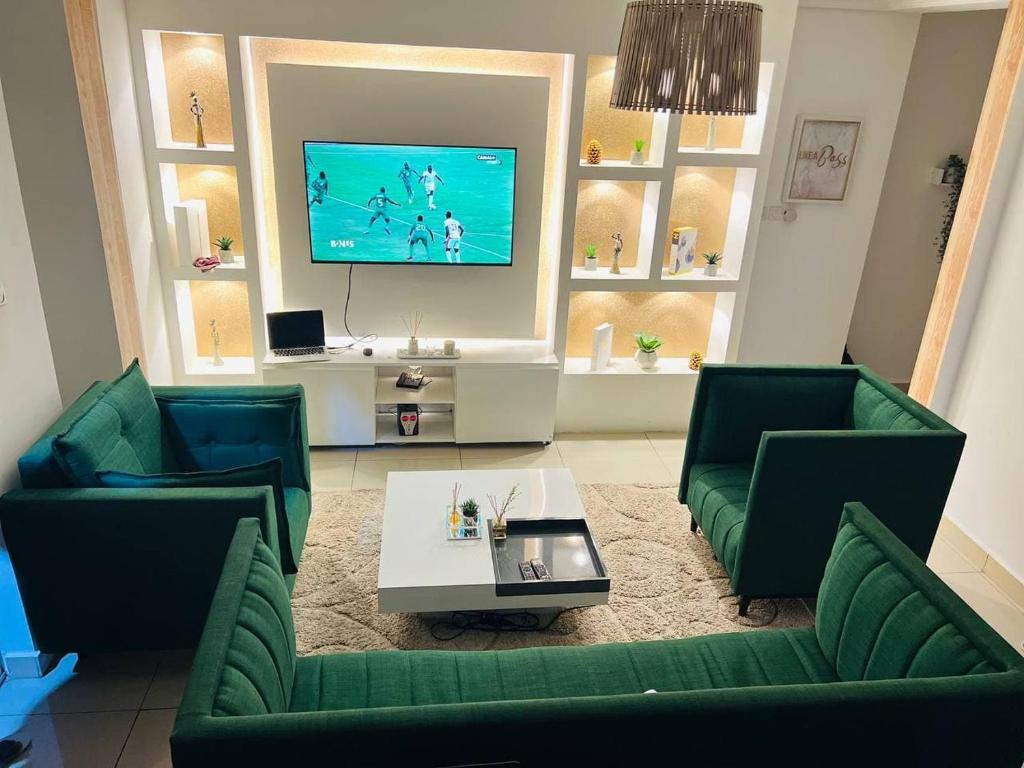 a living room with two green couches and a tv at Appartement cosy Green bonapriso in Douala