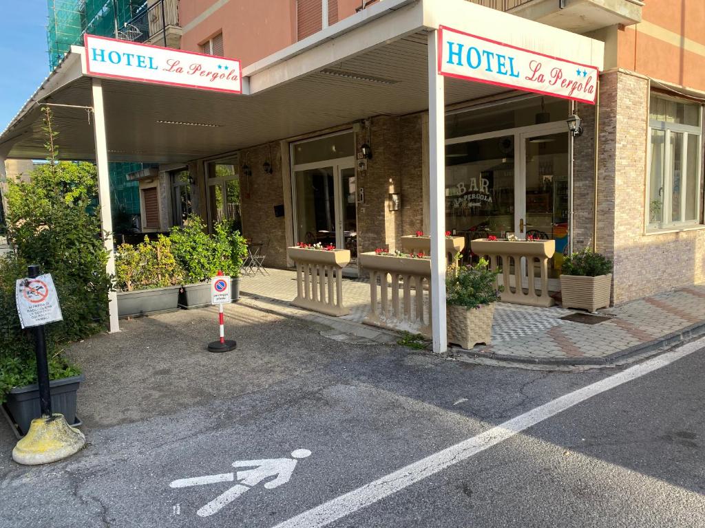 un hotel con un cartel frente a un edificio en Hotel La Pergola, en Loano