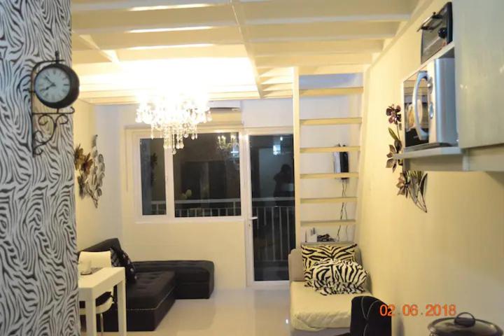 sala de estar con reloj en la pared en SMDC Wind Residences 102 Loft Bedroom Facing Amenities with WIFI and Parking en Tagaytay