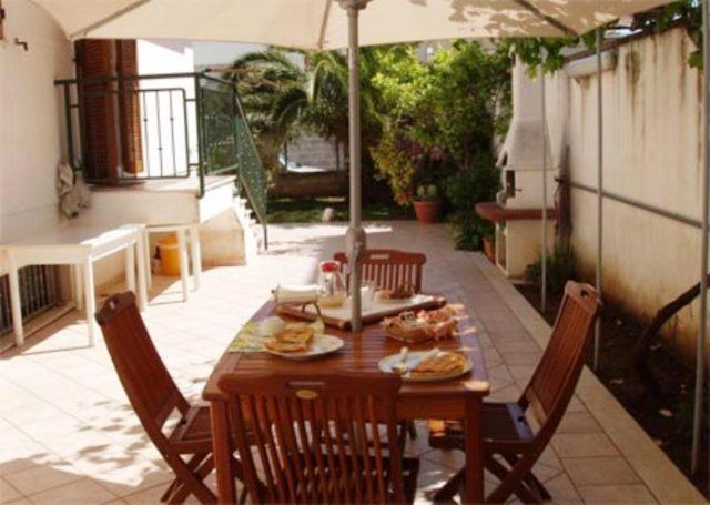 una mesa de madera con sillas y una sombrilla en el patio en Residenza Del Sole, en Surbo
