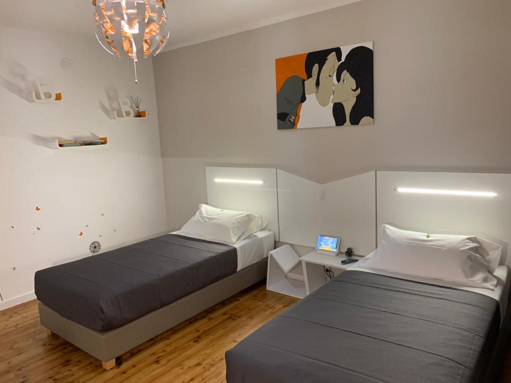 1 dormitorio con 2 camas, escritorio y lámpara de araña en BB BORGO BIELLA, en Candelo