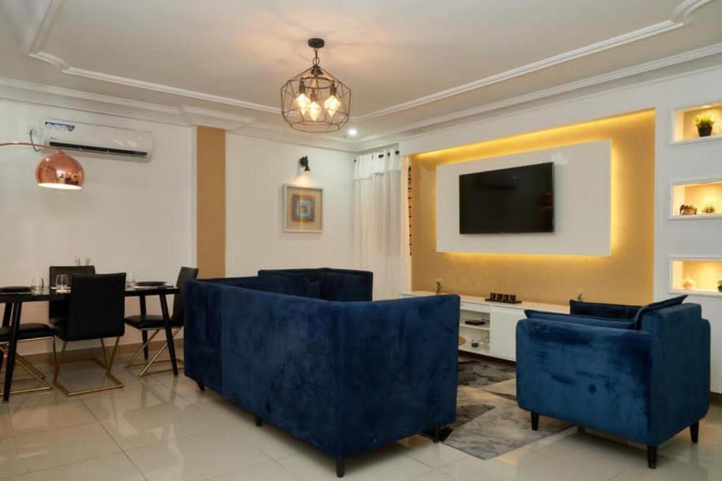 uma sala de estar com cadeiras azuis e uma televisão em Appartement cosy or bonapriso em Douala