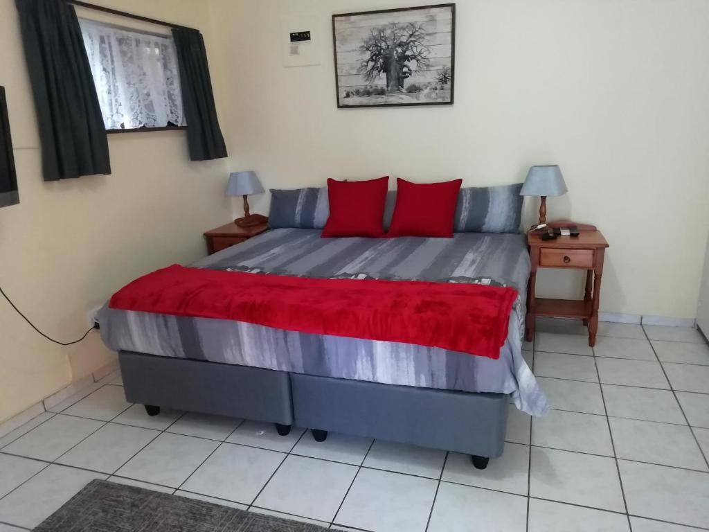 a bedroom with a large bed with red pillows at Anne's Cottage in Durban