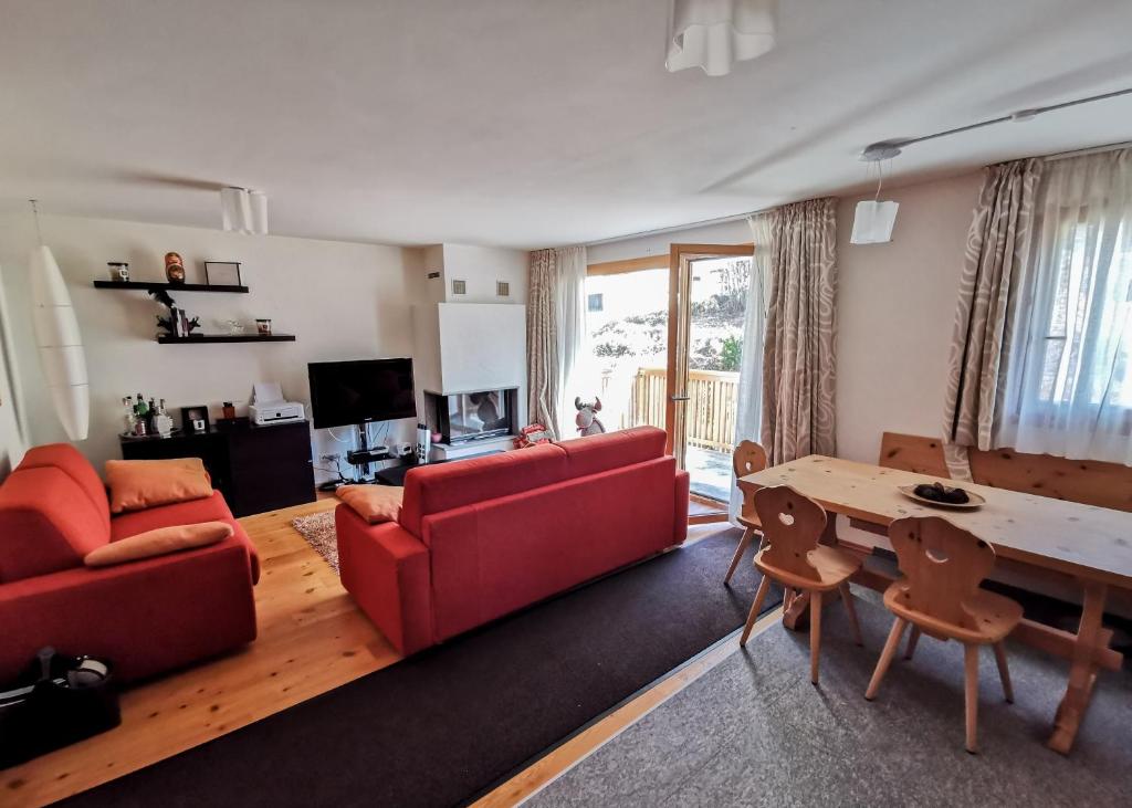 uma sala de estar com um sofá vermelho e uma mesa em Ca del Forno St Moritz em Maloja