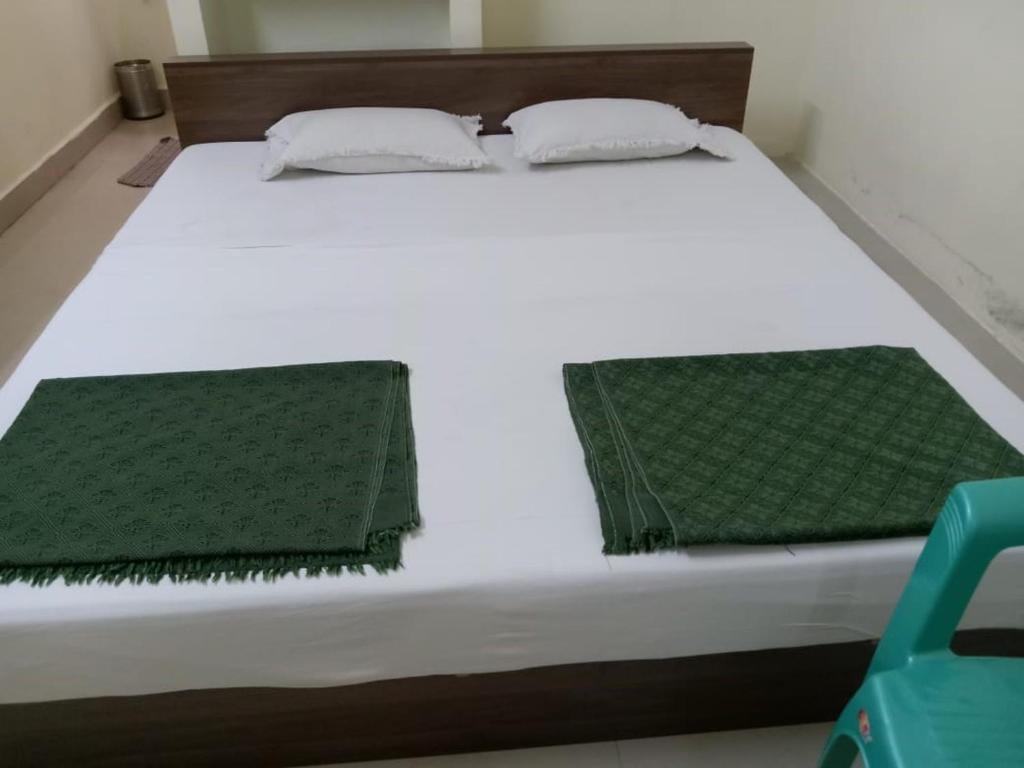 a bed with white sheets and green towels on it at BSSK Comforts Inn in Srīrangam