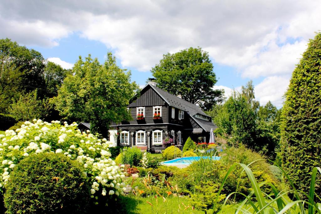 a black house with a garden in front of it at Penzion pod Železným Vrchem in Chřibská