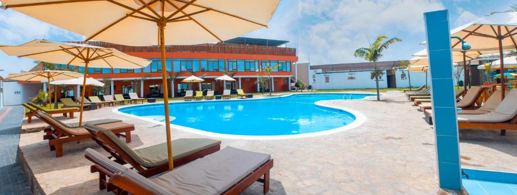 una piscina con sedie e ombrelloni accanto a un edificio di Hotel Resort Thiago a Chincha Alta