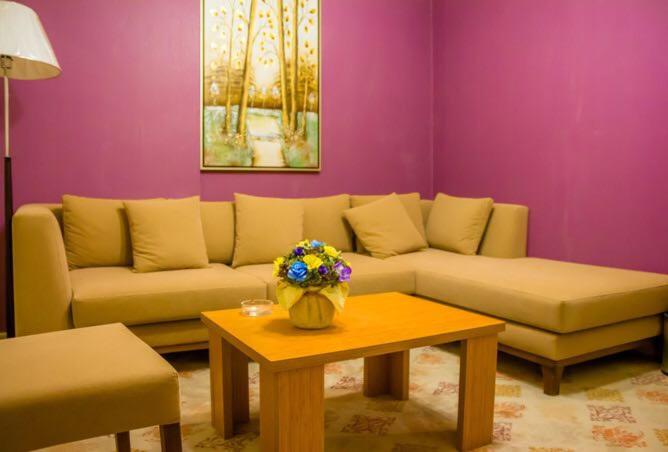 ein Wohnzimmer mit einem Sofa und einem Tisch mit Blumen in der Unterkunft Al-Telal Tower Apartment 2318 in Mekka