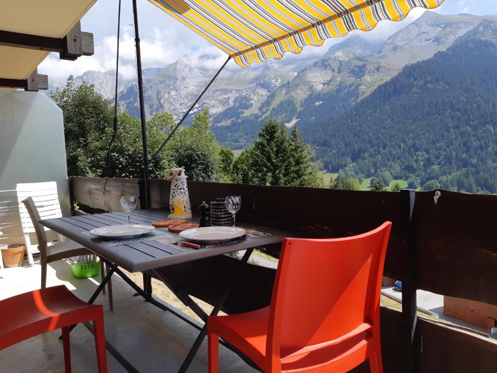 a table and chairs on a balcony with a view of mountains at Le Soladret - 2 pièces 4 étoiles - Vue extraordinaire sur les Aravis in La Clusaz