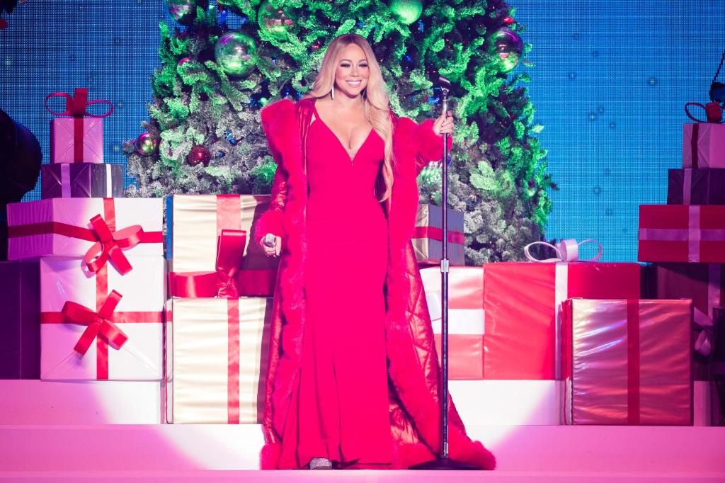 a woman in a red dress standing in front of presents at Mariah Carey’s Ultimate Holiday Experience in New York City in New York