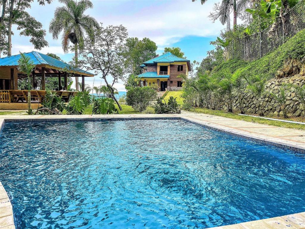 - une piscine en face d'une maison dans l'établissement Green Village By Hospedify, Hermosa Villa En Las Alturas con Piscina, Billar, y BBQ, à Jarabacoa