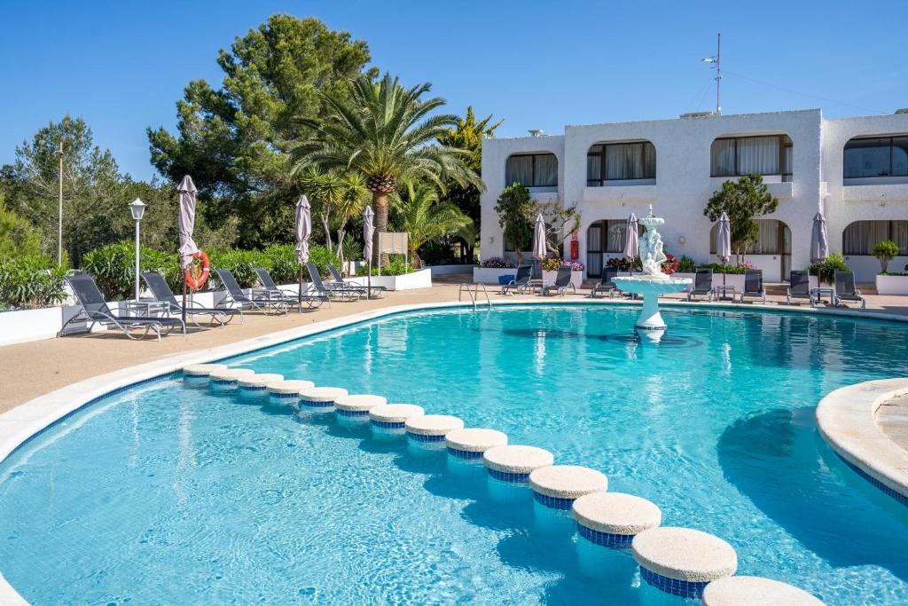 a large swimming pool with chairs and a building at Apartamentos Barbarroja - Formentera Break in Playa Migjorn