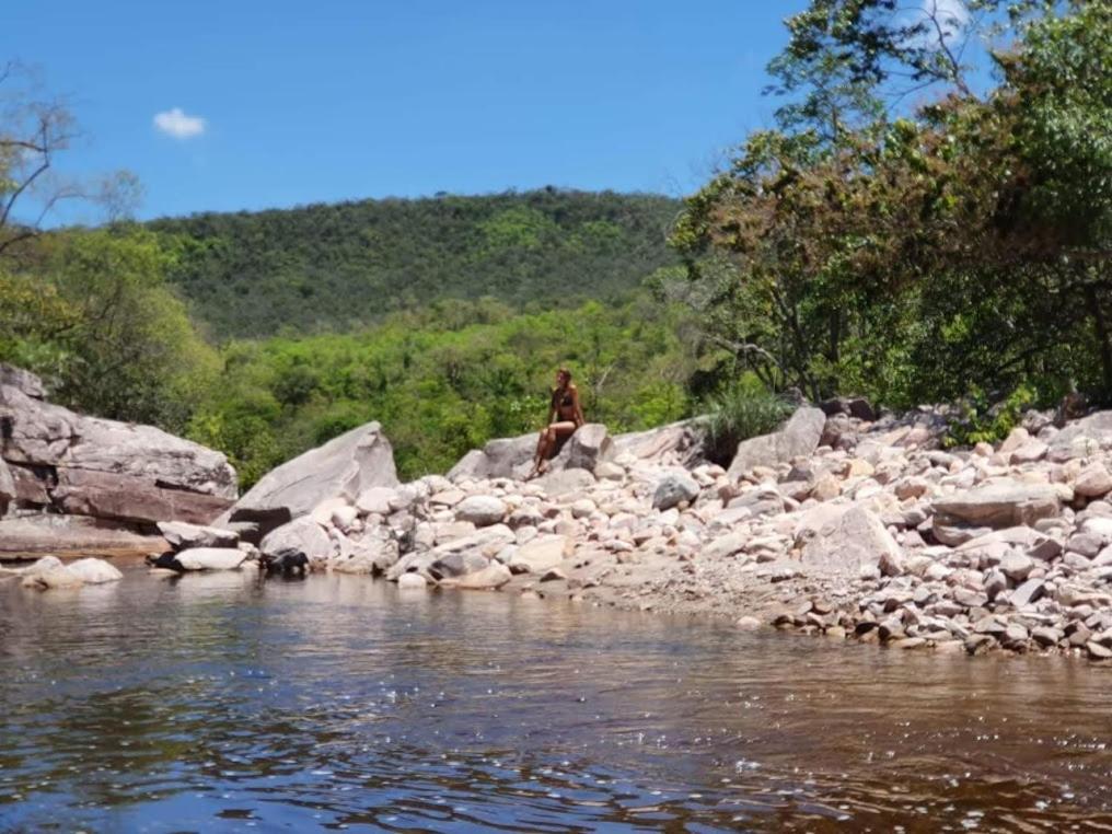 Ein Mann steht auf Felsen neben einem Fluss in der Unterkunft Casa AMAR Piscinas Naturais in Lençóis