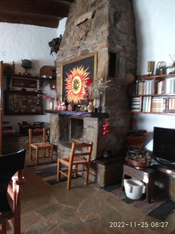 a stone fireplace in a room with chairs and a table at Eleni Country Cottage 2 in Feneos