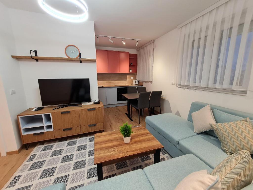 Rita Apartment في Gjakove: غرفة معيشة مع أريكة زرقاء وتلفزيون