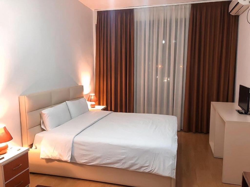 1 dormitorio con cama blanca y ventana grande en Hotel Argenti, en Shkodër