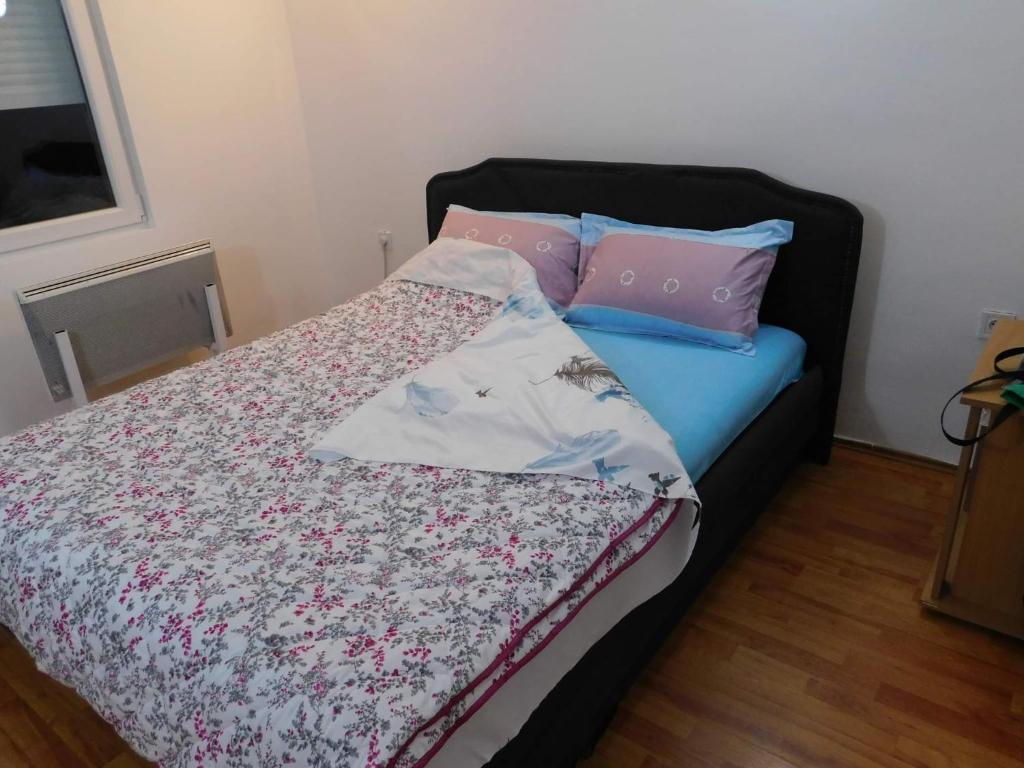 a bed with two pillows on top of it at Apartman Bagdala in Kruševac