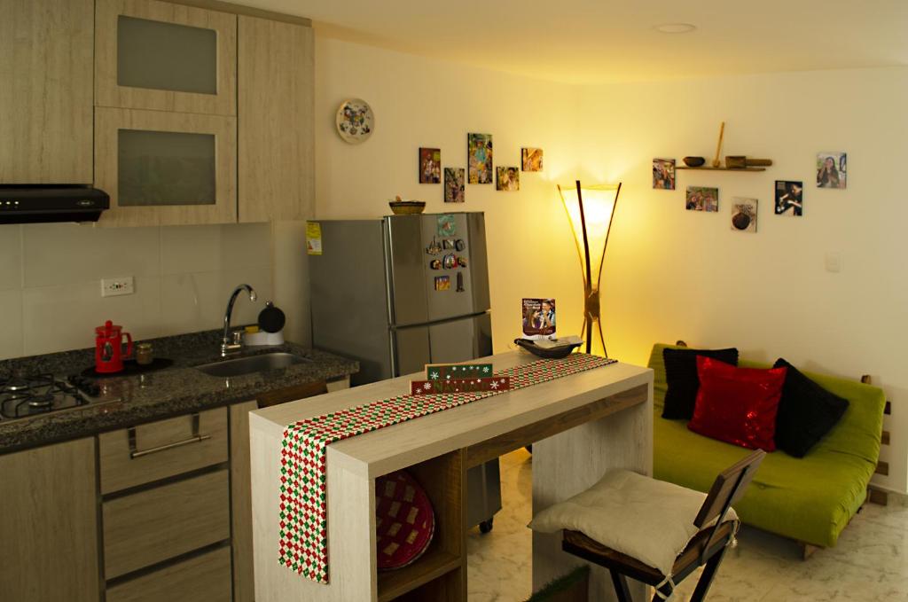une cuisine avec un comptoir et un canapé vert dans l'établissement Cálido apartaestudio en La Castellana, à Armenia