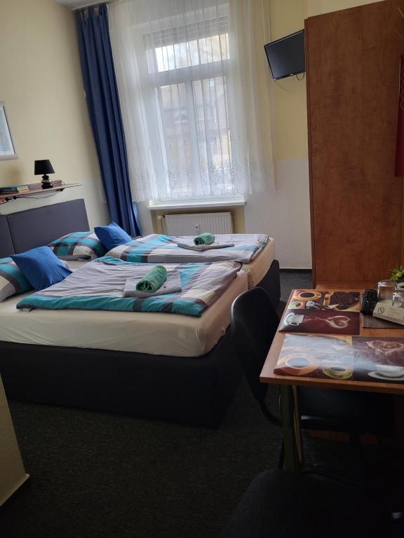 two beds in a room with a table at Pension Hubertus in Berlin