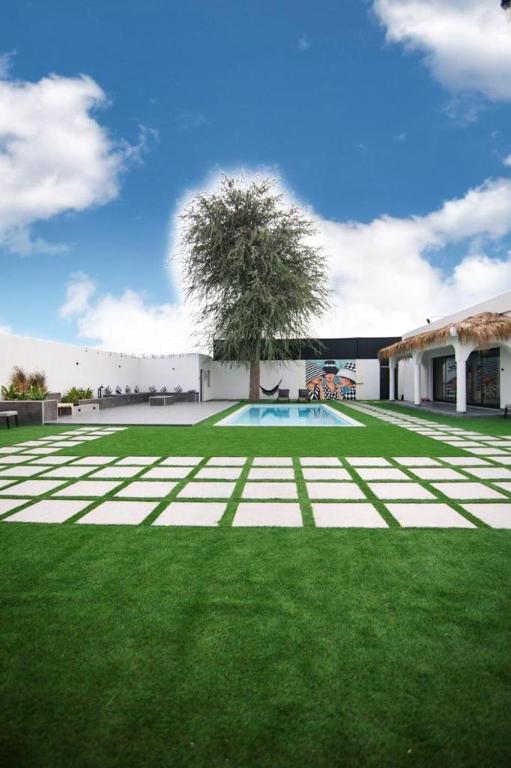un cortile verde con una piscina e un albero di Two Palm - Villa a Ras al Khaimah