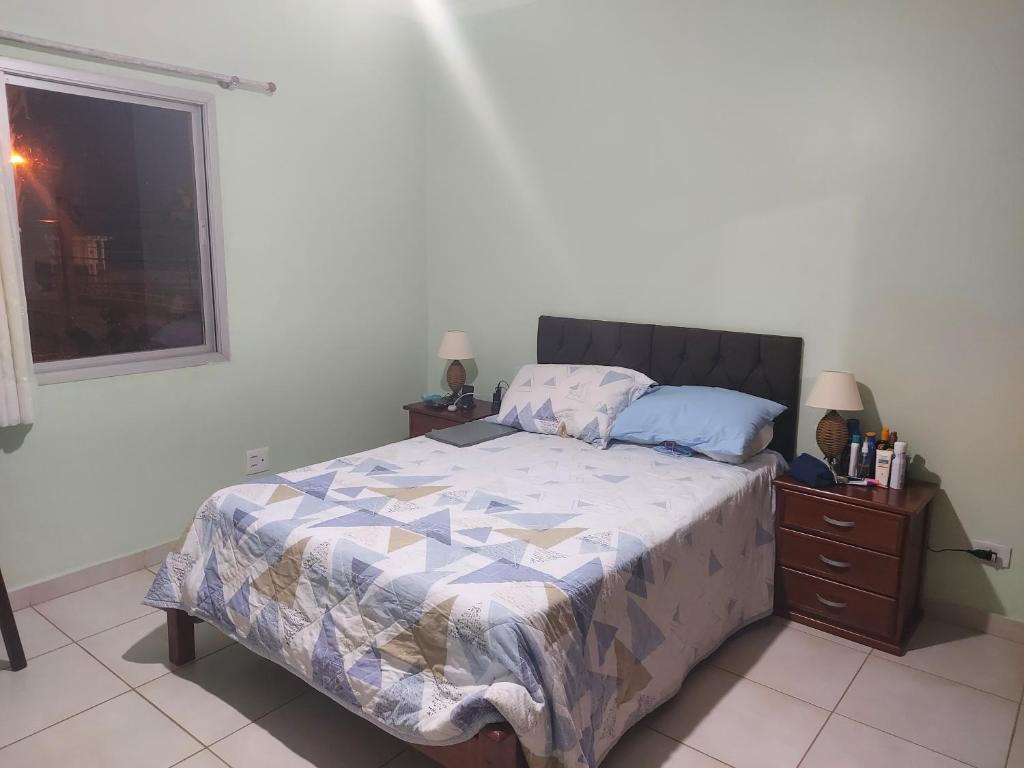 ein Schlafzimmer mit einem Bett, einer Kommode und einem Fenster in der Unterkunft Edifício Galassi in Praia Grande