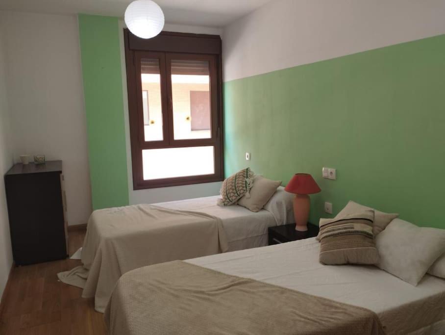 Precioso piso con ducha hidromasaje VUT-LE-726 في أستورغا: سريرين في غرفة بجدران خضراء ونافذة