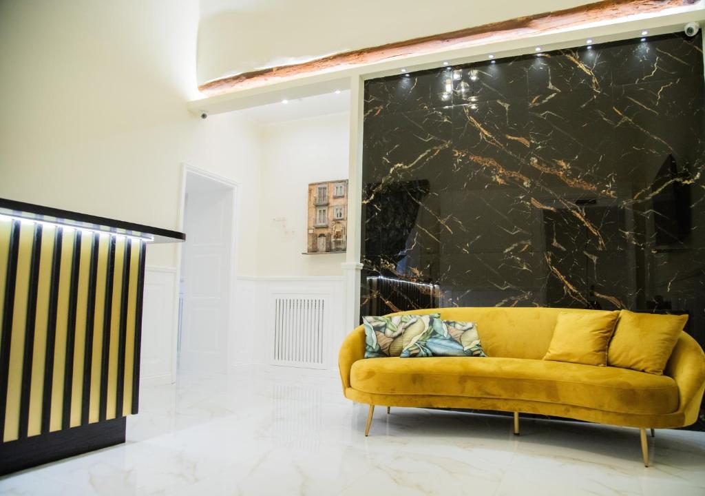 ein gelbes Sofa in einem Zimmer mit schwarzer Wand in der Unterkunft Gentile Suite in Neapel