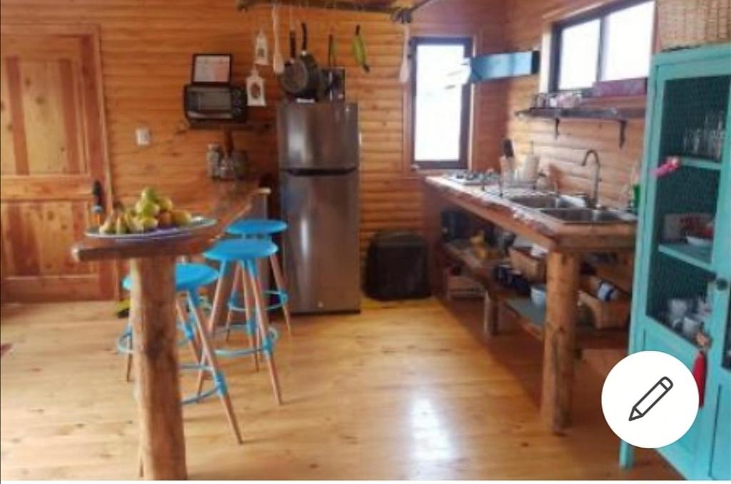 cocina con nevera y encimera con mesa en Casa en el campo Olmue, en Granizo