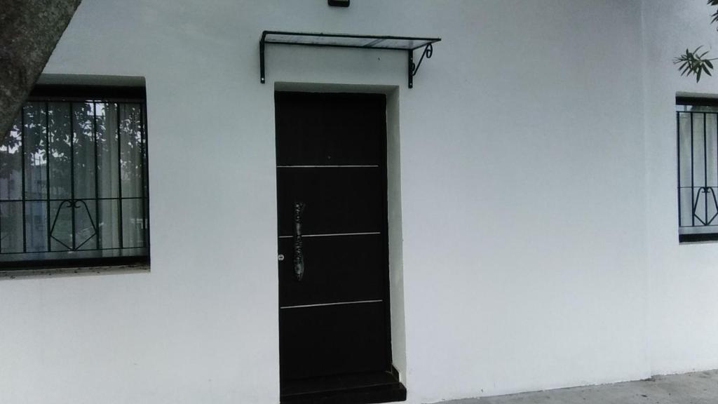 a black door on the side of a white building at Villa Elisa,La Plata Apart II in Villa Elisa
