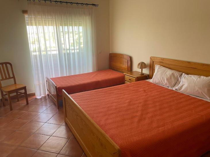 een slaapkamer met 2 bedden, een stoel en een raam bij t2 armação de pêra in Armação de Pêra