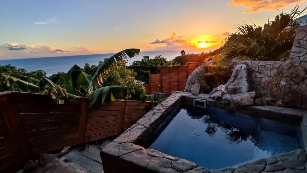 a backyard pool with a sunset in the background at Sunset Sapphire in Case-Pilote