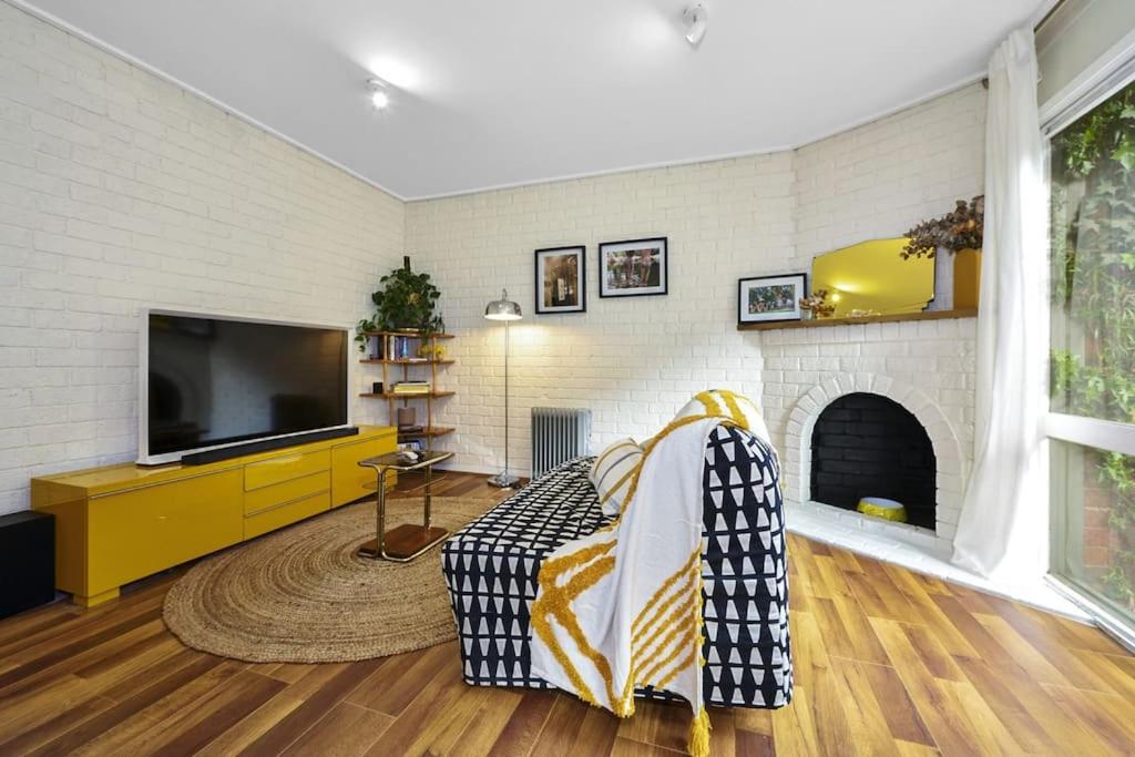 a living room with a couch and a tv at Carlton Dream: Leafy 2bed 2bath Lygon Str Townhouse in Melbourne