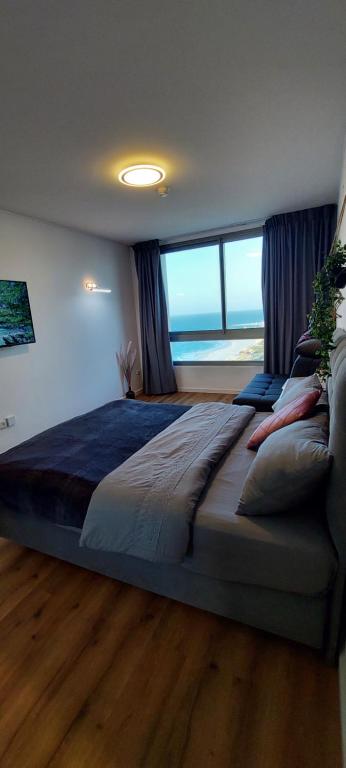 a bedroom with a large bed with a view of the ocean at מגדל C1 in Netanya