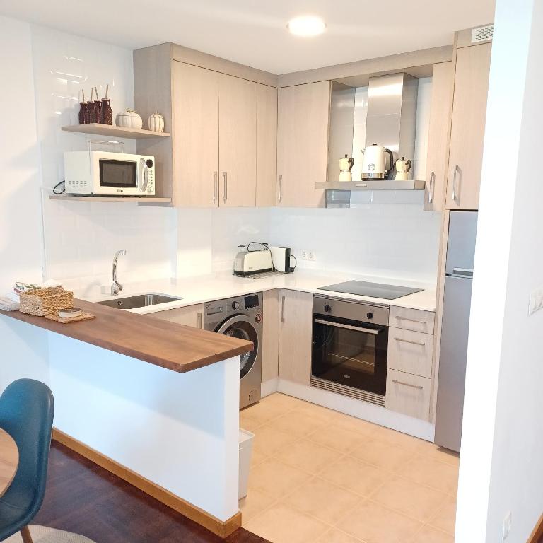 a white kitchen with a sink and a stove at Apartamento Mar de Sal in Finisterre