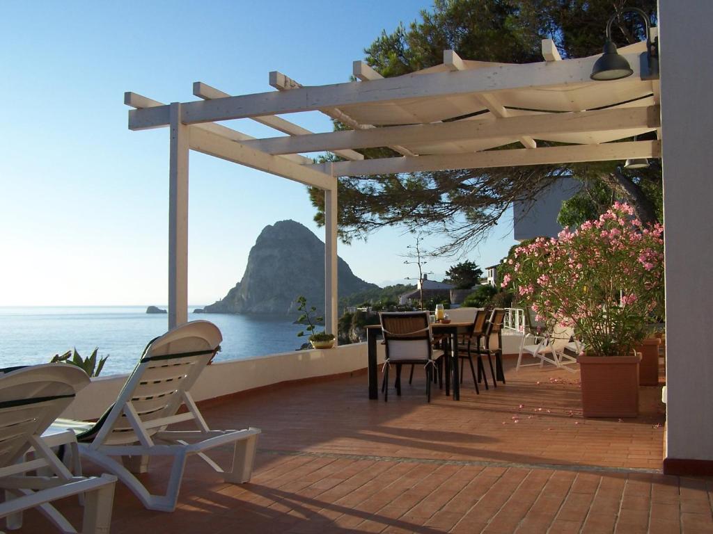 a patio with chairs and tables and a view of the ocean at VILLA LAURA MARIE in Porticello