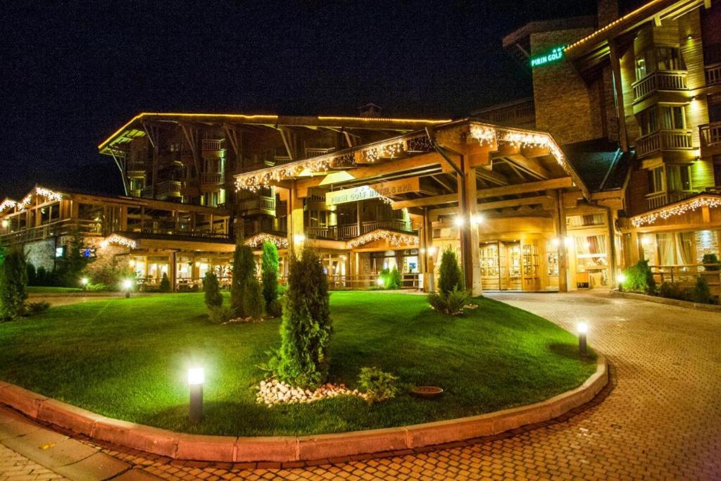 a building with a green lawn in front of it at night at Pirin Golf Private Apartments & Studios in Razlog